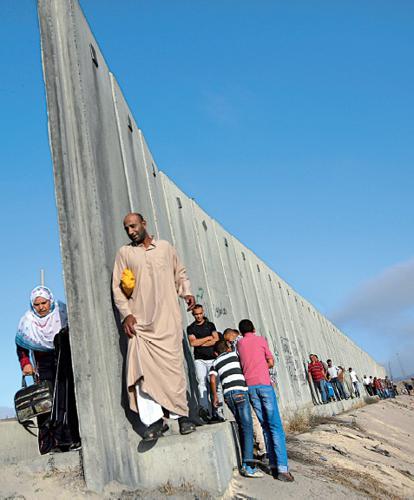 Palestinesi camminano lungo il muro che separa Cisgiordania da Gerusalemme